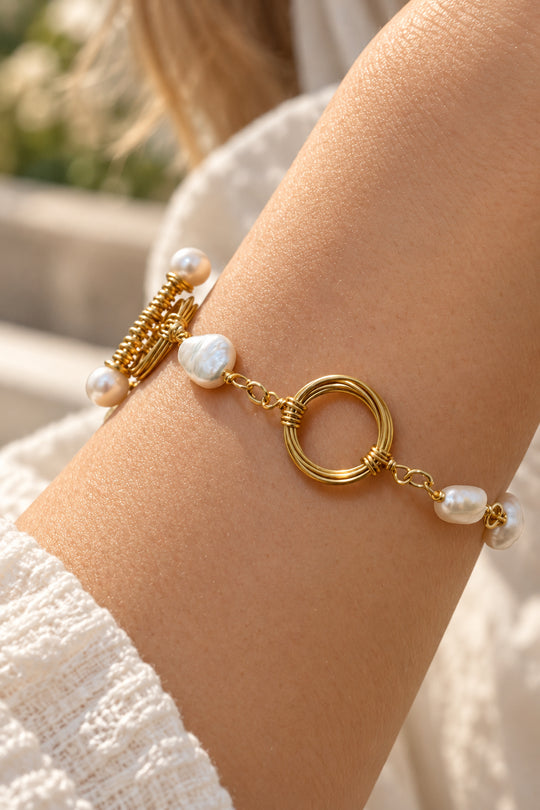 Model trägt das APAERZ AURELIA Armband mit großer verzierter Süßwasserperle und goldfarbenen Ringelementen am Handgelenk